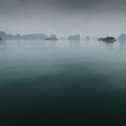 Boats drifting on calm waters with fog