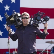 Shane Hurlbut holding two cameras in front of American flag