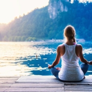 Woman meditating on dock by lake