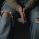 Boy's hands pressed together and torn jeans