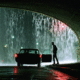 Torrential raining with car and silhouette of man under bridge