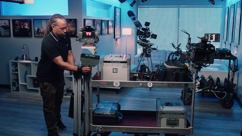 Assistant Camera loads lens cart with tripod legs