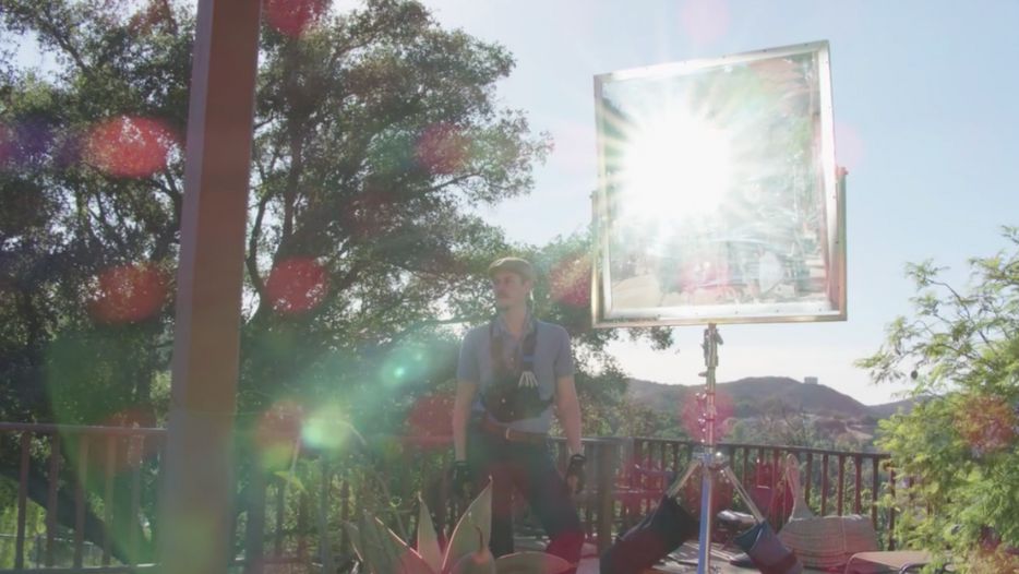 The sun bounces off a mirror board to light a day interior scene 