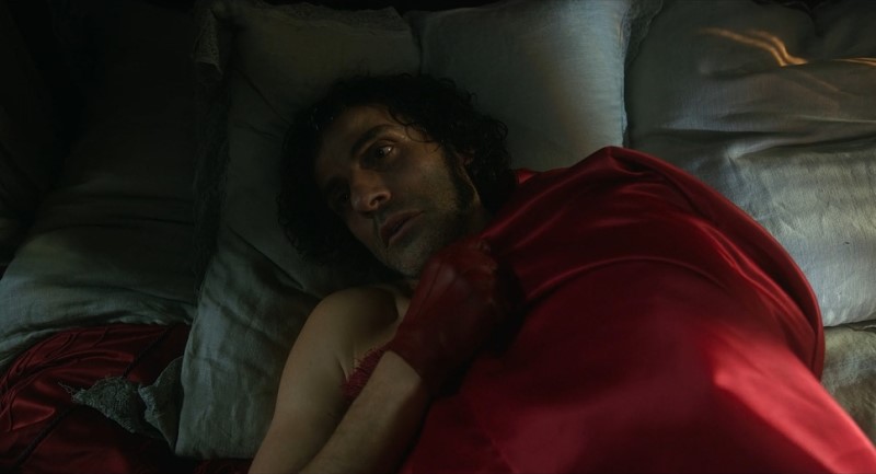 Dr. Frankenstein (Oscar Isaac) with blood red gloves and blanket