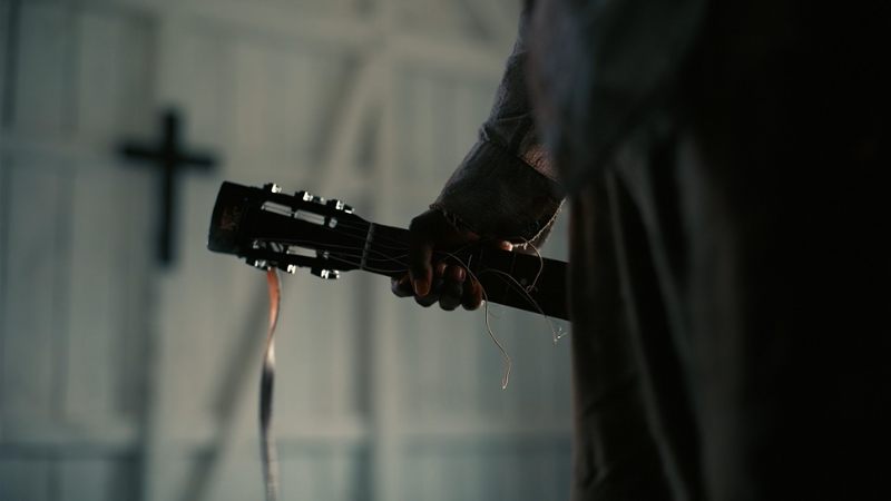 Sammie holding broken guitar in Sinners